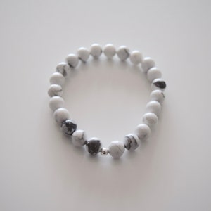 May include: A white and black marble beaded bracelet with a silver bead accent.