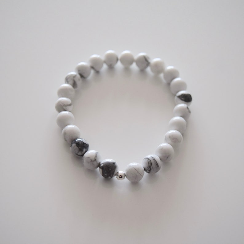 May include: A white and black marble beaded bracelet with a silver bead accent.