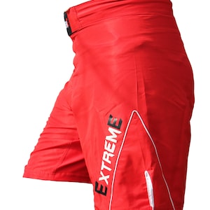 K&ouml;nnte beinhalten: Rote Sport-Shorts mit wei&szlig;en Paspeln und dem Wort "EXTREME" in Schwarz auf der Seite.