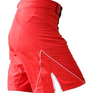 K&ouml;nnte beinhalten: Rote Sport-Shorts mit wei&szlig;em Besatz und einem seitlichen Schlitz. Die Shorts haben einen elastischen Bund mit schwarzem und gr&uuml;nem Besatz.