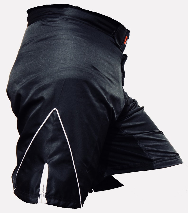 K&ouml;nnte beinhalten: Schwarze Sport-Shorts mit wei&szlig;em Besatz und einem kleinen orangen Logo am Bund.