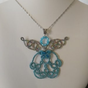 May include: A silver chain necklace with a blue and iridescent angel pendant. The angel is made of wire and has a beaded halo.