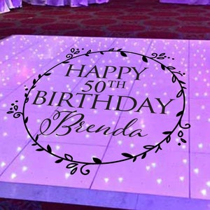 May include: A purple dance floor with white lights and a black circle with the text "Happy 50th Birthday Brenda" in a decorative wreath.