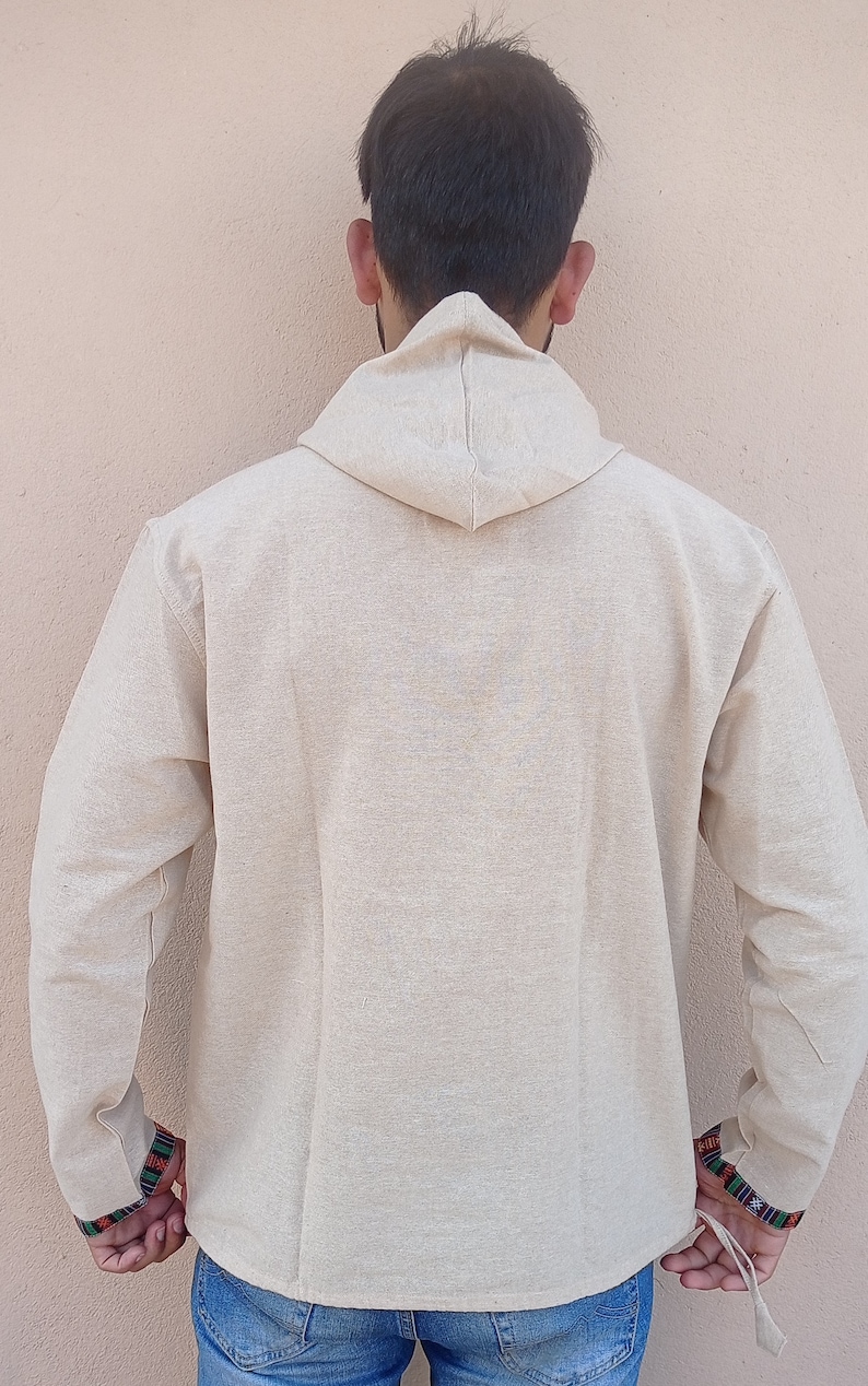 May include: A beige hooded long-sleeved shirt with colorful trim on the cuffs. The shirt is made of a soft, comfortable fabric.