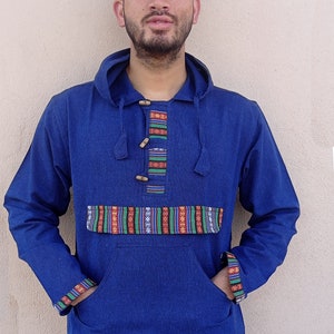 May include: A blue hooded sweatshirt with a colorful patterned trim around the neck, pockets, and cuffs. The sweatshirt has a drawstring hood and wooden button closures.