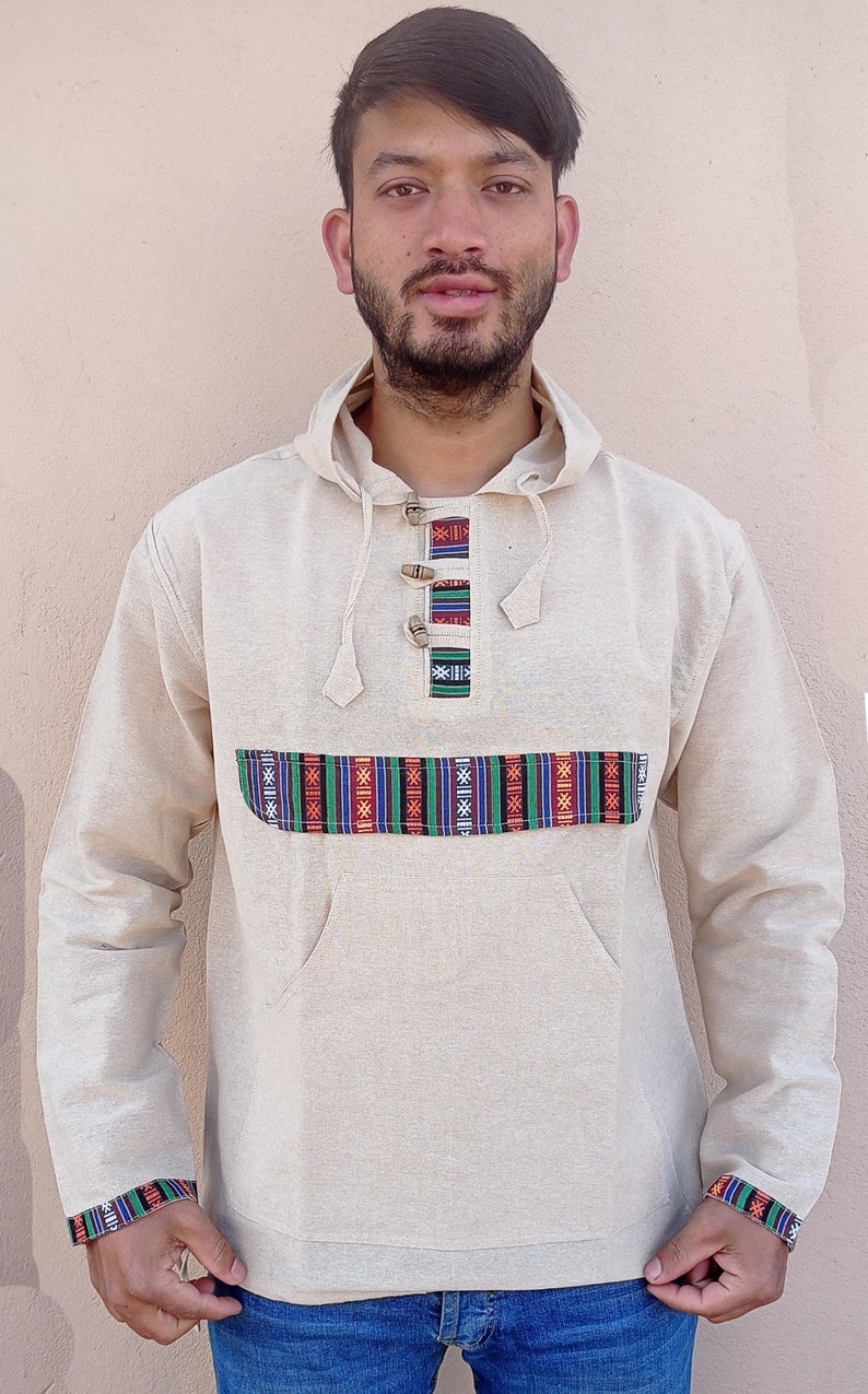 May include: A beige hooded sweatshirt with a colorful patterned band across the chest and matching trim on the sleeves. The sweatshirt has a kangaroo pocket and a drawstring hood.