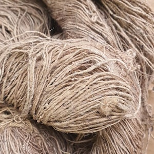 May include: Close-up of several bundles of natural-colored twine. The twine is tightly wound, with visible strands and a slightly rough texture. The color is a warm, earthy brown, suggesting a natural fiber product, ideal for crafting or packaging.