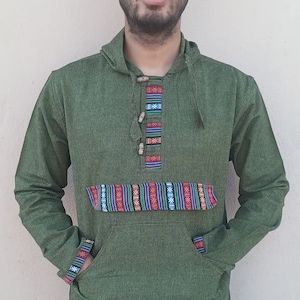 May include: A green hooded sweatshirt with a colorful patterned band across the chest and a drawstring at the bottom. The sweatshirt has a kangaroo pocket and a button closure at the neck.