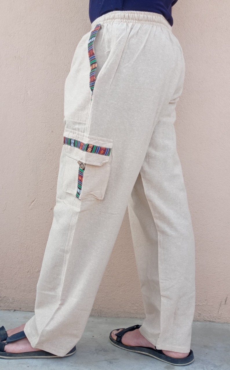 May include: Beige linen pants with a colorful patterned trim along the side seams and a large cargo pocket on the left leg.