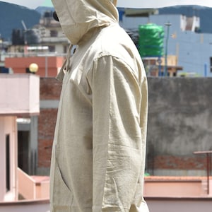 Pu&ograve; includere: Una camicia di lino beige con cappuccio, maniche lunghe e chiusura con bottoni. La camicia ha una vestibilit&agrave; rilassata e uno stile casual.