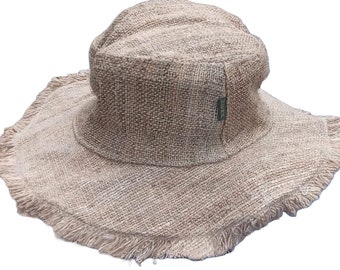 May include: A wide-brimmed, natural-colored, hemp hat with a frayed edge. The hat has a slightly rounded crown and a green label on the side.