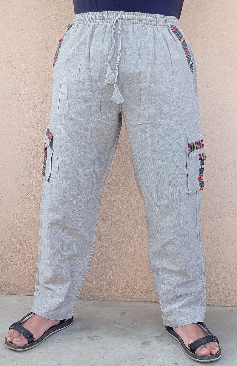 May include: Gray linen pants with a drawstring waist and side pockets. The pockets have colorful embroidered trim.