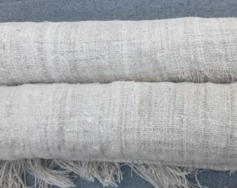 May include: Two rolls of natural linen fabric with frayed edges. The fabric is a light beige color and has a woven texture.