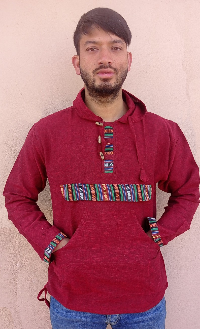 May include: A maroon hooded sweatshirt with a patterned band across the chest and a drawstring at the bottom. The sweatshirt has a kangaroo pocket and a button closure at the neck.