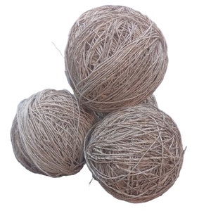 May include: Three balls of natural fibre twine, likely jute or hemp, are stacked on top of each other. The twine is a light brown colour and has a rough texture.