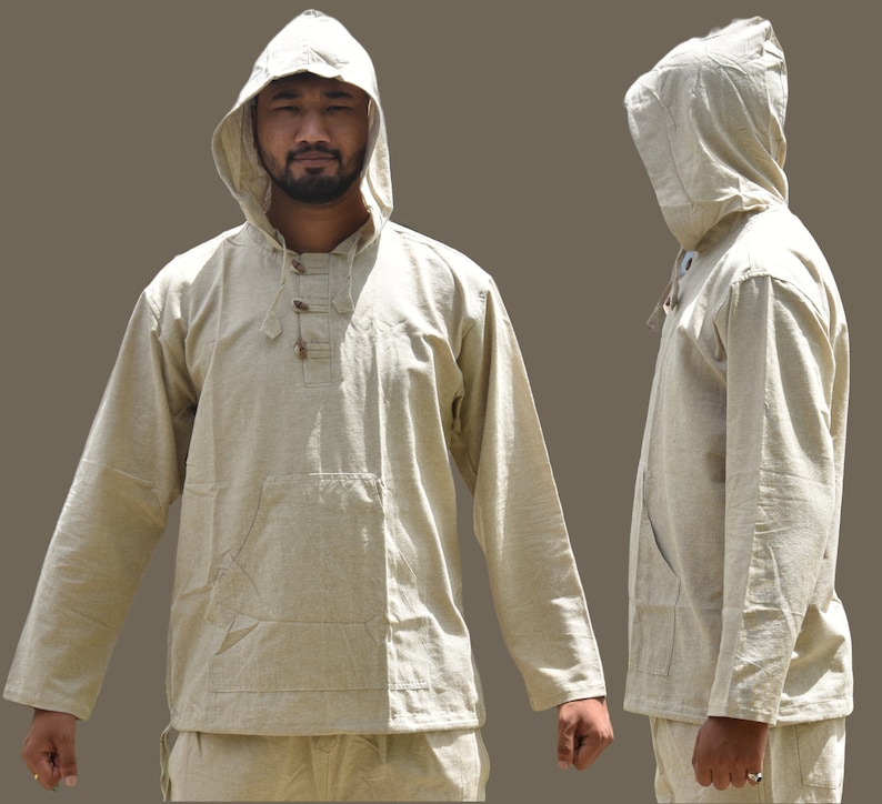 Pu&ograve; includere: Una camicia beige con cappuccio a maniche lunghe e chiusura con bottone al collo. La camicia ha una tasca sul davanti e un cordoncino in vita.