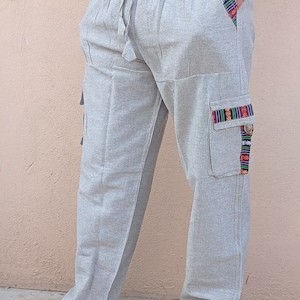 May include: Gray linen pants with a drawstring waist and decorative trim on the pockets. The pants have a relaxed fit and are perfect for casual wear.