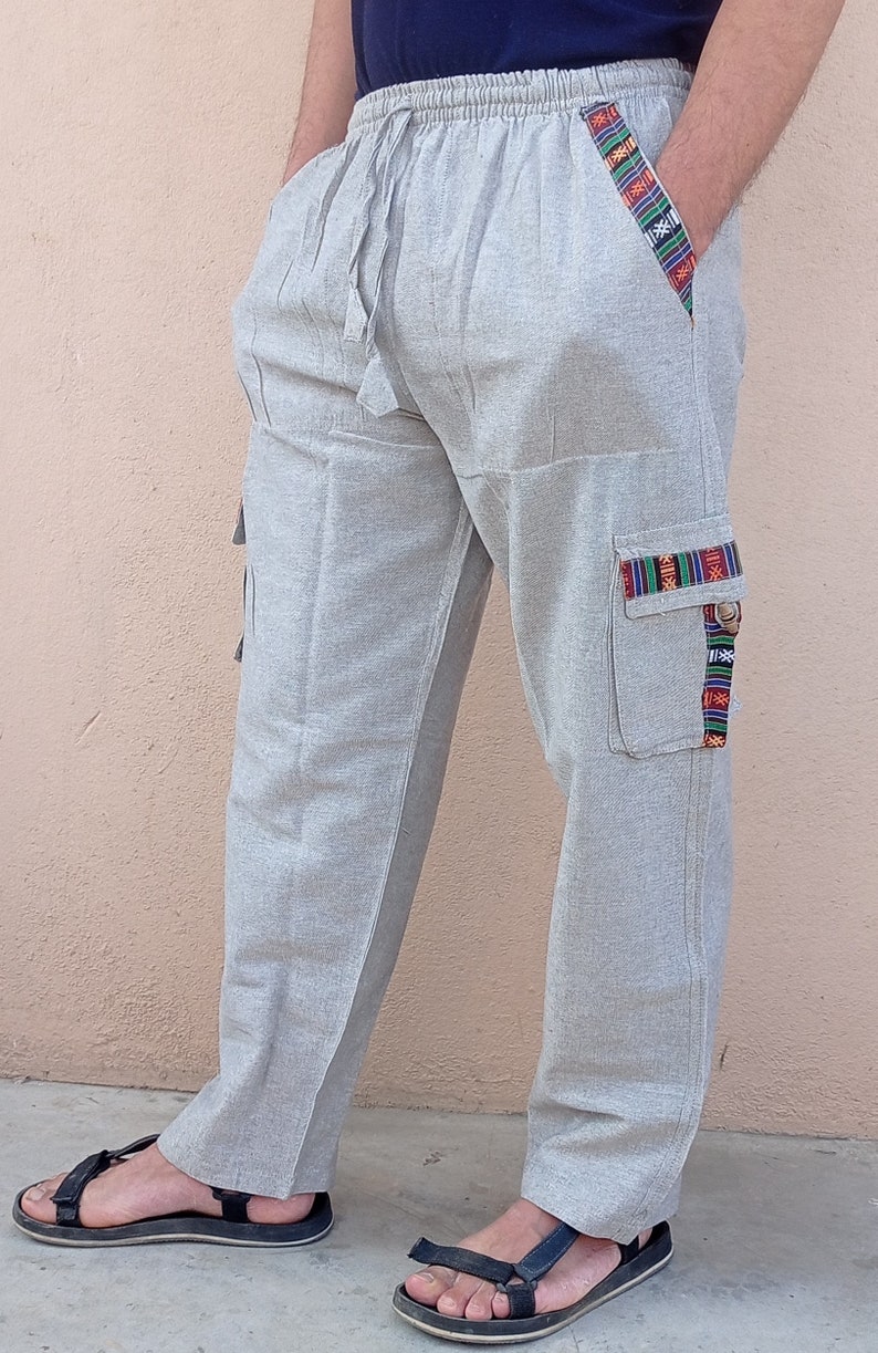 May include: Gray linen pants with a drawstring waist and decorative trim on the pockets. The pants have a relaxed fit and are perfect for casual wear.