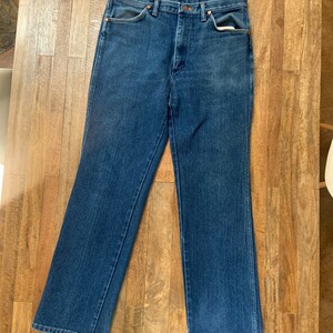 May include: A pair of blue denim jeans with a classic straight leg fit. The jeans have a button fly and five pockets.