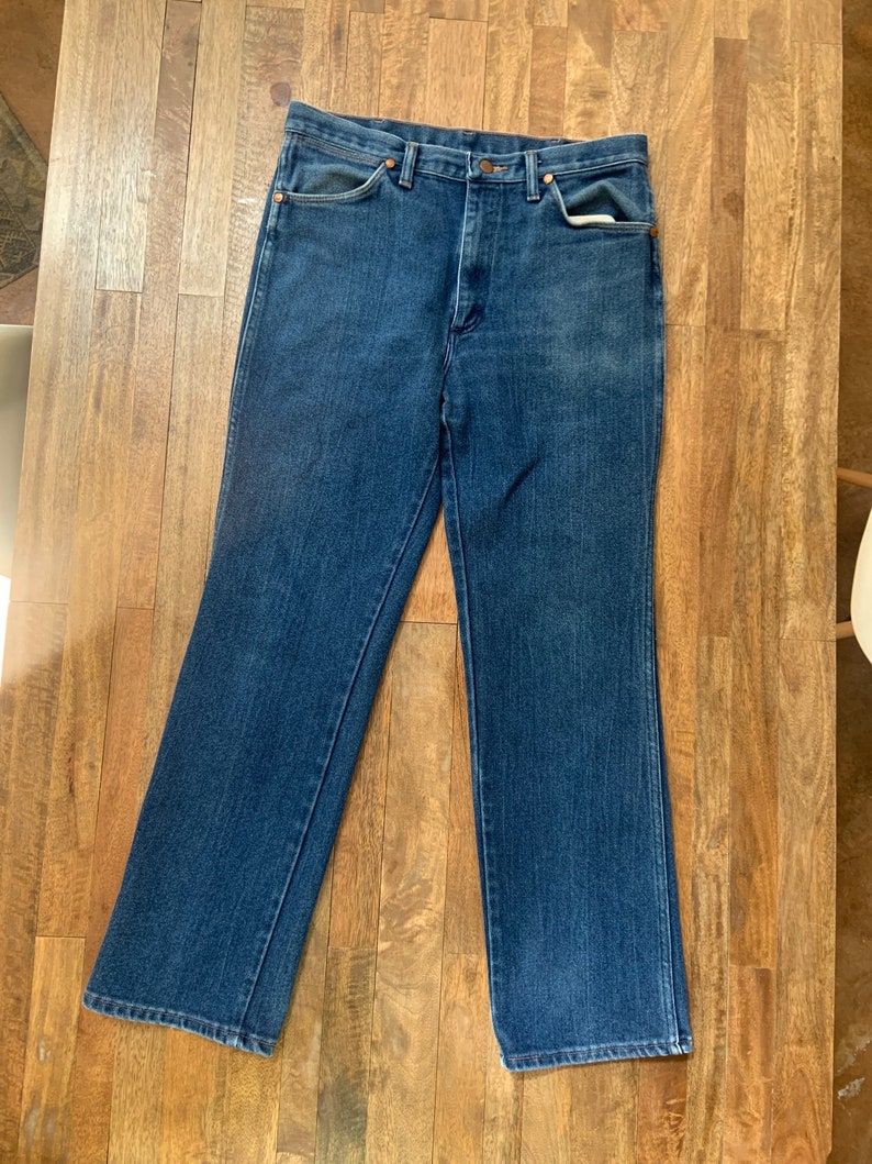 May include: A pair of blue denim jeans with a classic straight leg fit. The jeans have a button fly and five pockets.