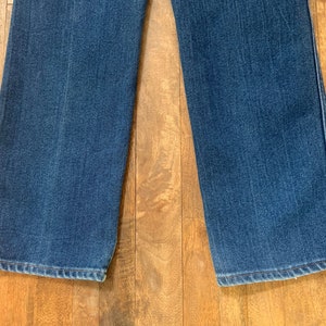 May include: Close-up of the bottom hems of a pair of blue denim jeans. The jeans have a straight leg style and are made of a soft, comfortable fabric.