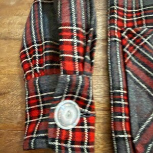 Może przedstawiać: Zbliżenie na rękaw koszuli w czerwoną, czarną i białą kratę. Mankiety zapinane na srebrny guzik. Wz&oacute;r koszuli to klasyczny tartan, z mieszanką czerwonych, czarnych i białych linii.