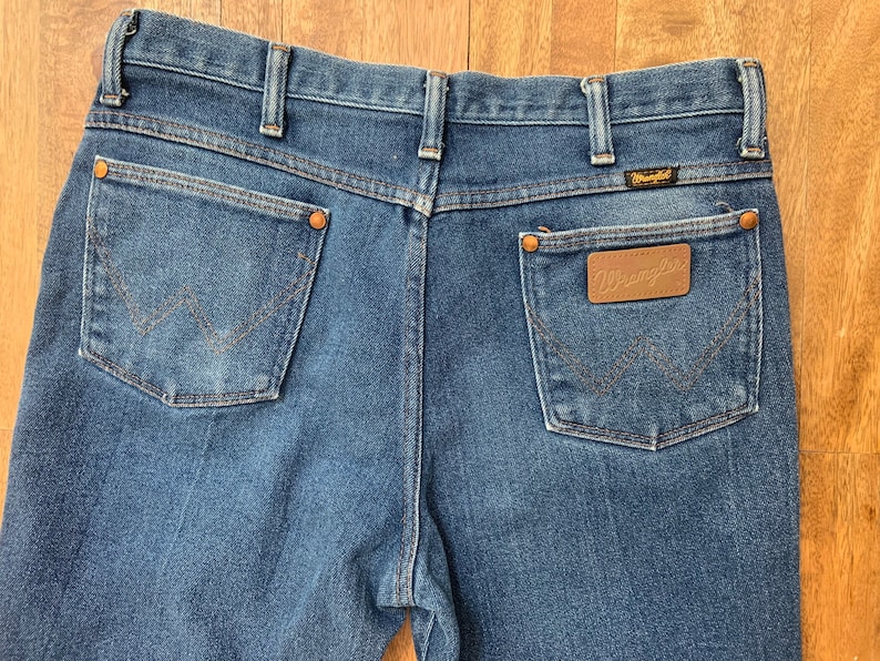 May include: A pair of blue denim jeans with a brown leather patch on the back pocket that says "Wrangler".