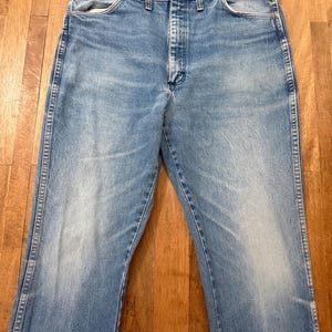 May include: Light blue denim jeans with a classic five-pocket design. The jeans have a faded wash and a straight leg fit. The jeans are made of durable denim material and feature a button and zipper closure.