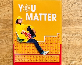 May include: A rectangular magnet with a yellow background and the words "YOU MATTER" in white. The magnet features an illustration of a person in a yellow raincoat and jeans, with a periodic table of elements at the bottom.