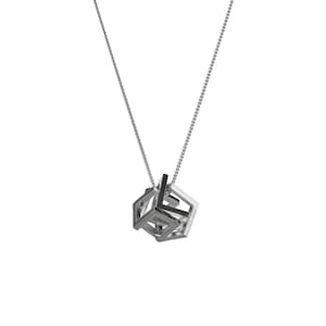 Peut inclure: Un collier en argent avec un pendentif géométrique composé de plusieurs carrés imbriqués.