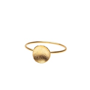Op de afbeelding: Een gouden ring met een getextureerde, ronde schijf in het midden.