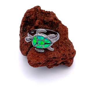 Può includere: Un anello d'argento con un design a forma di tartaruga in opale verde.