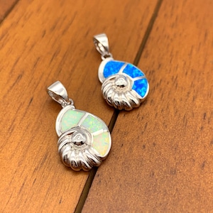 May include: Two silver nautilus shell pendants with opal inlay. One pendant has a blue opal and the other has a white opal.