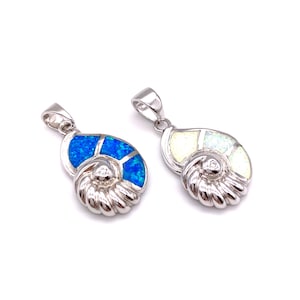 Puede incluir: Dos colgantes de plata en forma de concha de nautilus con incrustaciones de ópalo. Un colgante tiene un ópalo azul y el otro un ópalo blanco.