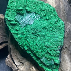 以下が含まれることがあります： 緑色の孔雀石の岩に、白い結晶の塊が埋め込まれています。岩はざらざらしていて質感があり、結晶は透明でキラキラしています。