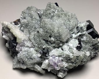 Op de afbeelding: Een cluster van zwarte Schorl-tourmalijnkristallen ingebed in een matrix van witte en grijze kwartskristallen. De kristallen zijn scherp en goed gedefinieerd, met een glanzende afwerking.