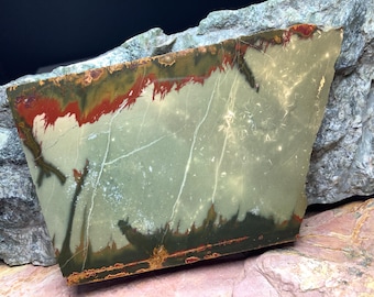 May include: A slab of polished green, white, and red jasper with a unique pattern. The jasper has a smooth, polished surface and is a beautiful example of this type of stone.