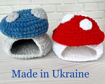May include: Three handmade crochet mushroom-shaped pet beds. One is blue with white spots, another is red with white spots, and the third is gray. The beds are made of soft, textured yarn. The text "Made in Ukraine" is at the bottom.