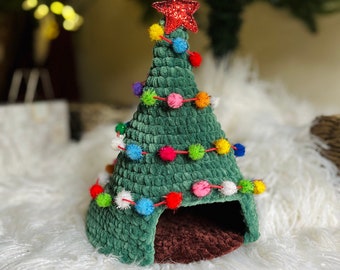 May include: A green crocheted Christmas tree shaped pet bed with a red star on top and colorful pom-poms around the base.