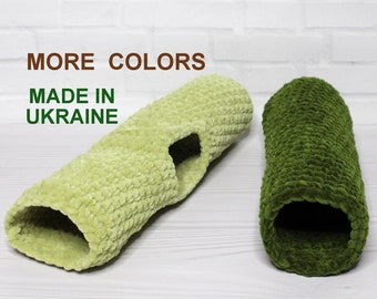 May include: Two crocheted cat tunnels, one in a light green color and the other in a dark green color. The tunnels are made of soft yarn and have a hole in the middle. The text "MORE COLORS" and "MADE IN UKRAINE" is visible above the tunnels.