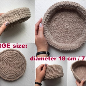May include: A large, beige, crocheted basket with a diameter of 18 inches. The basket is made of soft, fuzzy yarn and has a round shape.