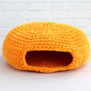 May include: A bright orange crocheted cat bed shaped like a dome with a round entrance hole.