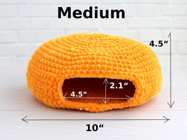 May include: A medium-sized, orange crocheted pet bed with a round shape and a hole for entry. The bed measures 10 inches in diameter, 4.5 inches in height, and the hole is 4.5 inches wide and 2.1 inches tall.