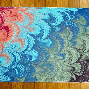 May include: Abstract marbled paper with a gradient of colors, starting with red and orange at the top, transitioning to blue and green, and ending with dark purple and black at the bottom. The marbling creates a swirling, feather-like pattern.
