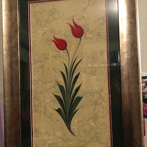 May include: A framed artwork featuring a traditional Turkish art style with two red tulips on a marbled background.