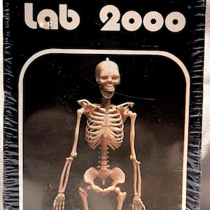 May include: A vintage "Lab 2000" assembly kit for a human skeleton model. The box features a detailed illustration of the assembled skeleton. The kit includes snap-fit pieces, movable joints, and is approximately 12 inches high.