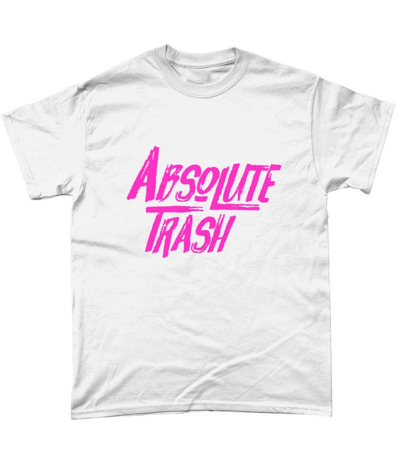 以下が含まれることがあります： ピンクの「ABSOLUTE TRASH」の文字がプリントされた白いTシャツです。