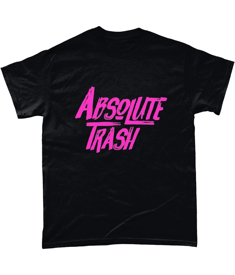 以下が含まれることがあります： ピンクのグラフィックが施された黒いTシャツ。スタイリッシュなフォントで「ABSOLUTE TRASH」と書かれています。