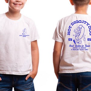 May include: White t-shirt with a blue graphic of a hot dog character on the back. The graphic says "Hot Diggity Dog" and "Best Tastes in Town".