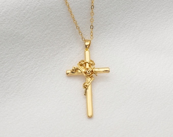 May include: A gold chain necklace with a gold cross pendant. The cross is decorated with a rose design.